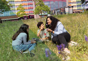 Groep kinderen en volwassene bij zonnebloemen, aandacht voor plant.
