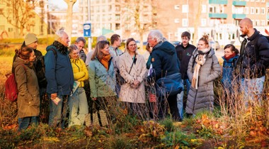 Groep mensen in een park luistert naar een spreker tijdens een excursie. De mensen dragen een dikke jas. Fotograaf: C Ewald Geerdink