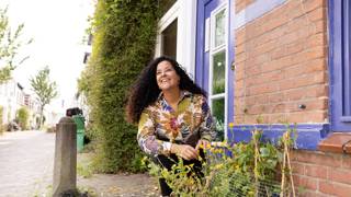 Persoon verzorgt planten in een kleine stadstuin.