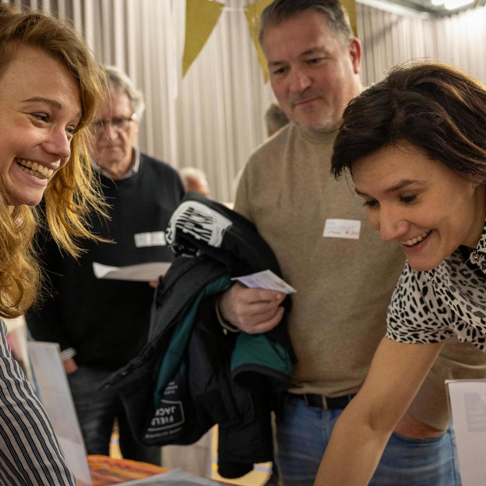 Twee vrouwen lachen en praten aan een informatiestand op Fondsen Festival