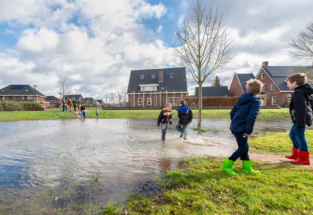 Kinderen spelend in grote plas water een speeltuin in een woonwijk