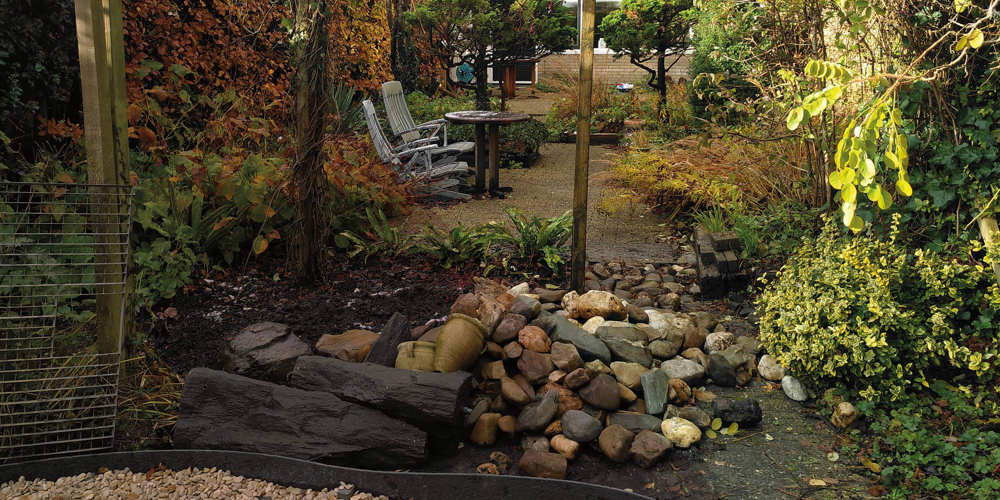 Tuin met stoelen, tafel, planten en grind, ingericht als buitenruimte