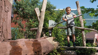 Kind speelt op met een waterbaan in een natuurlijke speelomgeving