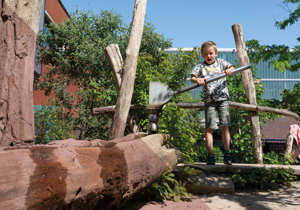 Kind speelt op met een waterbaan in een natuurlijke speelomgeving