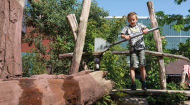 Kind speelt op met een waterbaan in een natuurlijke speelomgeving
