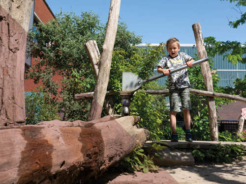 Kind speelt op met een waterbaan in een natuurlijke speelomgeving