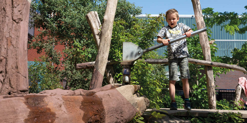 Kind speelt op met een waterbaan in een natuurlijke speelomgeving